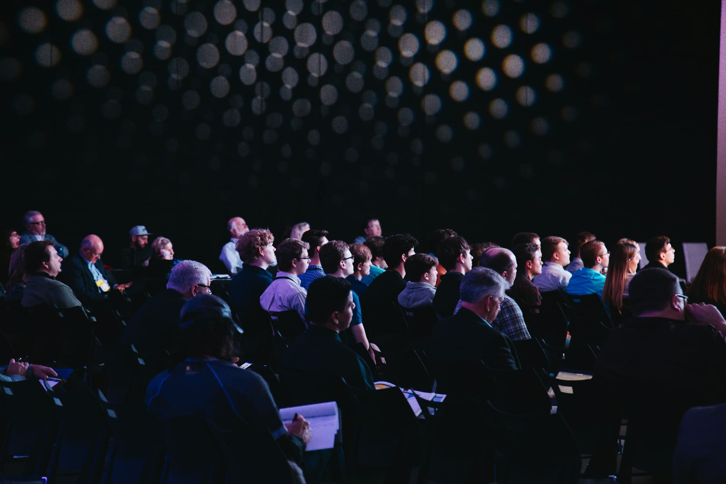Wide view of a live patient-education keynote to a seated audience
